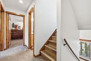 A hallway with wooden doors and a staircase leading to a bedroom.