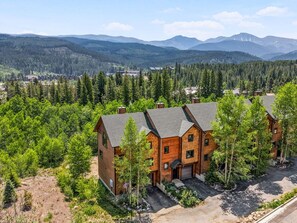 A multi-story wooden building with a driveway and a forested area in the background.