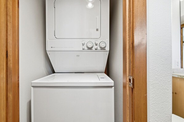 Eine weiße Waschmaschine ist von vorne in einem Waschraum zu sehen, der Holztüren und eine weiße Wand hat.