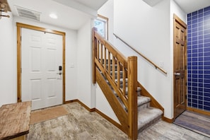 A staircase with wooden railings and carpeted steps leading to a door.