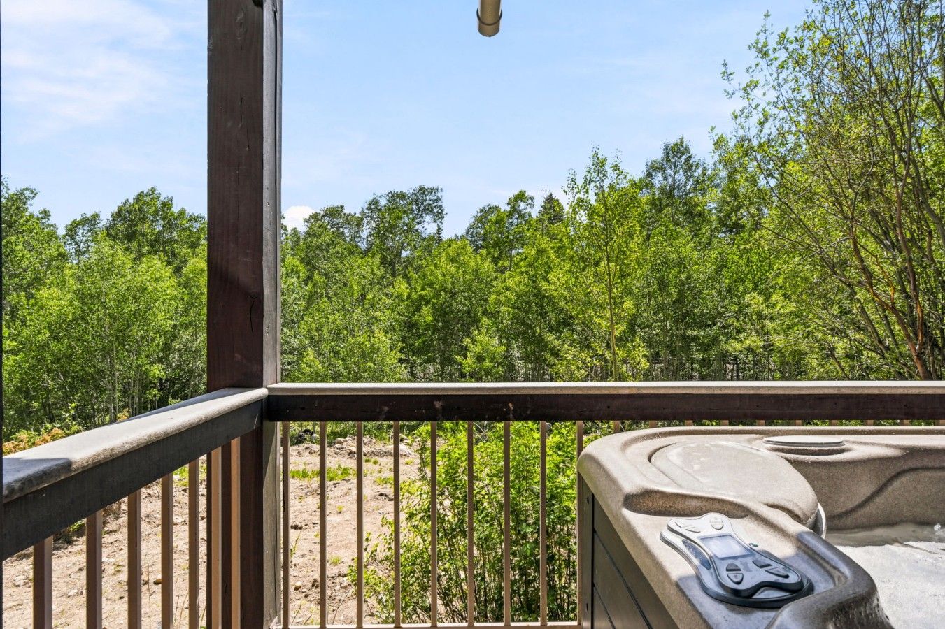 A wooden deck with a hot tub and a view of a forested area.