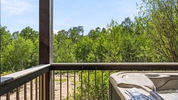 A wooden deck with a hot tub and a view of a forested area.