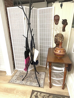 A room with a black floor lamp, a patterned rug, a wooden table with a vase, and decorative masks on the wall. - Private Artist's Suite & Garden | Commercial Drive (Vancouver)