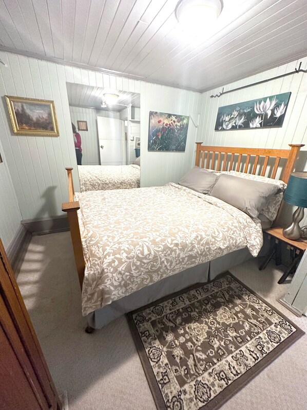 A bedroom with a bed, a nightstand, a mirror, and a rug. - Private Artist's Suite & Garden | Commercial Drive (Vancouver)