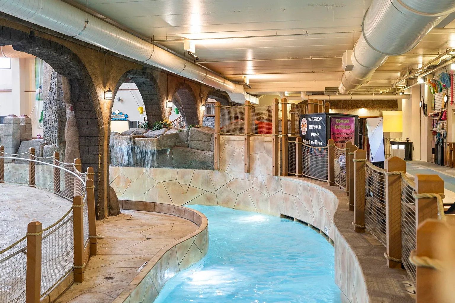 Un área de piscina interior con paredes de piedra y cubierta de madera.