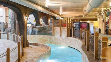 Un área de piscina interior con paredes de piedra y cubierta de madera.