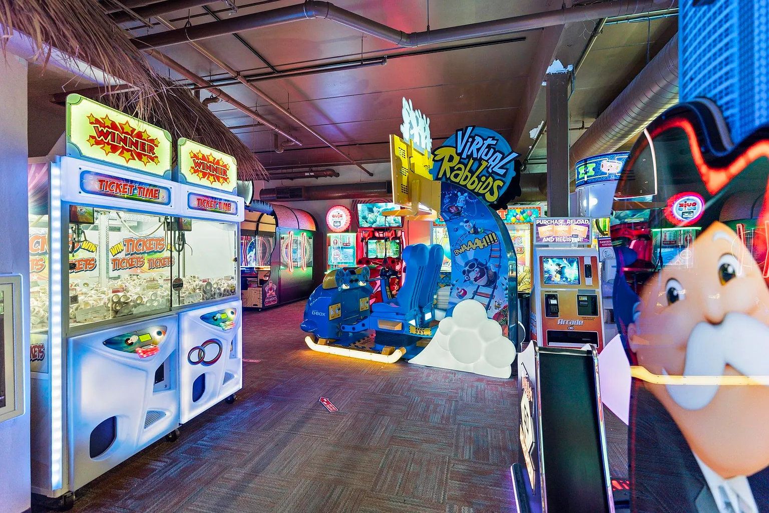 An indoor arcade with various gaming machines, including a 'Virtual Rabbids' ride and ticket machines.