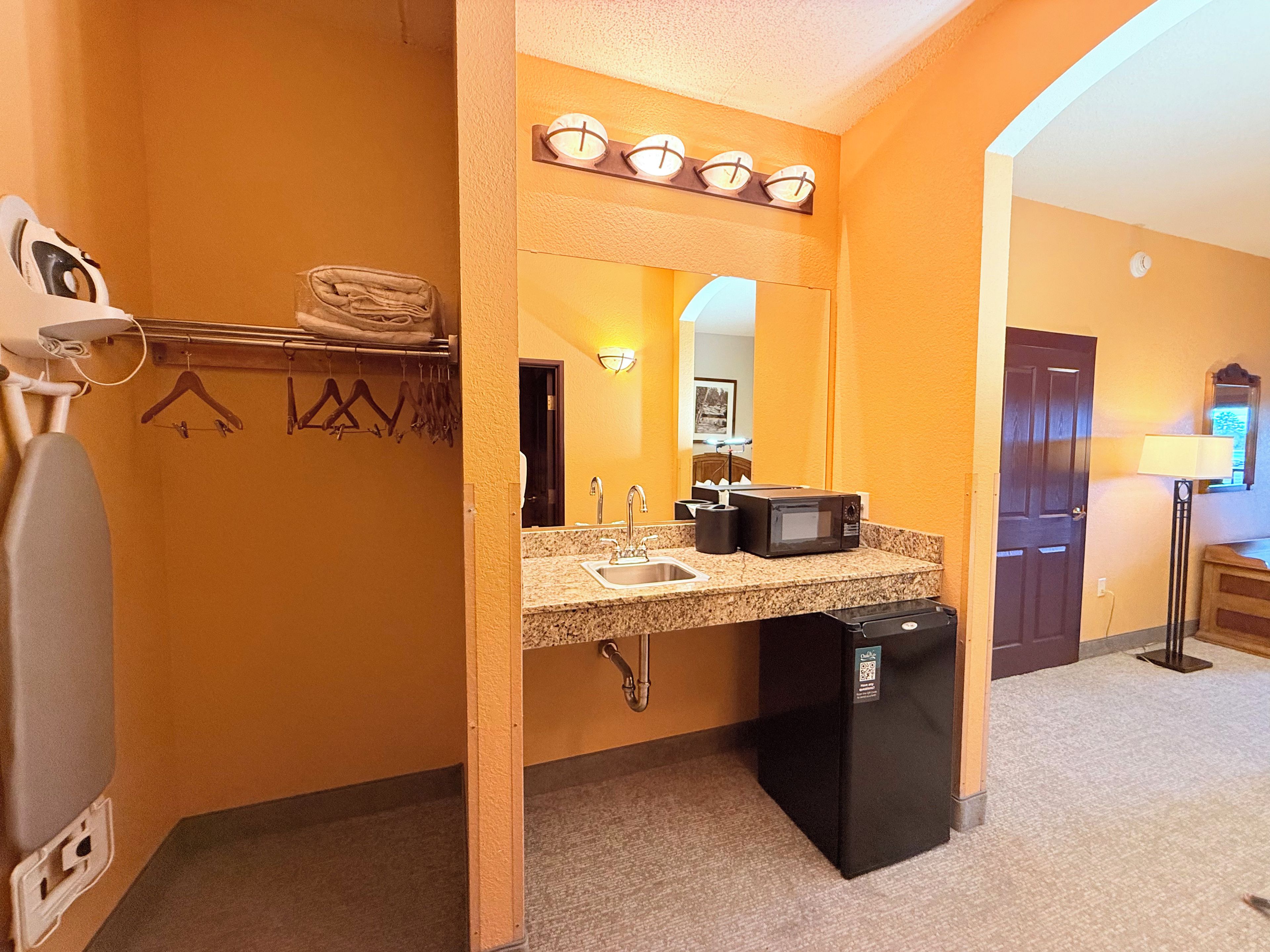 A hotel bathroom with a sink, mirror, towel rack, and a compact refrigerator.