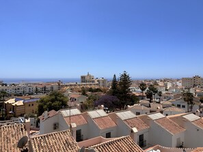 Eine Küstenstadt mit terrakotta-gedeckten Häusern, blauem Himmel und Blick aufs Meer.