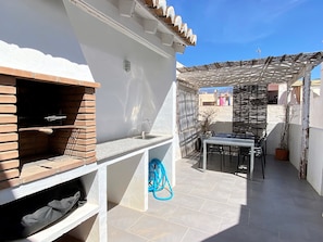 A patio with a barbecue grill, a sink, and a table with chairs. - Holiday House in Nerja With Sea Views (Nerja)