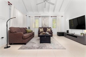 A modern living room with a brown sofa, a black coffee table, and a grey entertainment unit. - Richmond Retreat Gated Pool Beach Access (St. Ann's Bay)