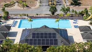 A swimming pool with blue water, surrounded by lounge chairs and palm trees. - Richmond Retreat Gated Pool Beach Access (St. Ann's Bay)