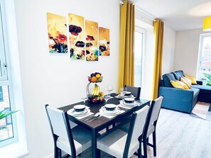 A dining area with a table set for two, a fruit bowl, and a fruit basket. - 2BR Apt Near Birmingham City Centre | Sleeps 6 (Birmingham)