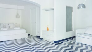A modern hotel room with a large bed, a bedside table, a wardrobe, and a bathroom with a mirror and window. - Vrbo Property (Campania)