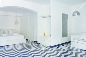 A modern hotel room with a large bed, a bedside table, a wardrobe, and a bathroom with a mirror and window. - Vrbo Property (Campania)