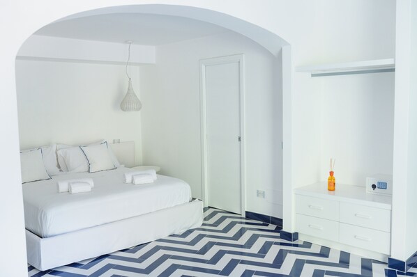 A modern hotel room with a bed, a white dresser, and a mirror. - Vrbo Property (Campania)