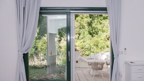 A room with a sliding glass door leading to an outdoor patio with a table and chairs. - Vrbo Property (Campania)