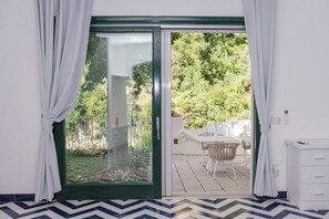 A room with a sliding glass door leading to an outdoor patio with a table and chairs. - Vrbo Property (Campania)