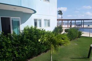 A modern building with a curved facade, a well-maintained lawn, and a view of a body of water. - Apartamento Pôr do Sol (Arraial do Cabo)