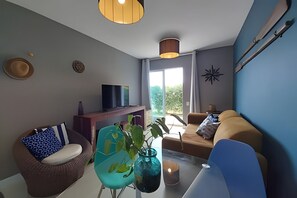 A modern living room with a sofa, a coffee table, and a TV on a wooden stand. - Apartamento Pôr do Sol (Arraial do Cabo)