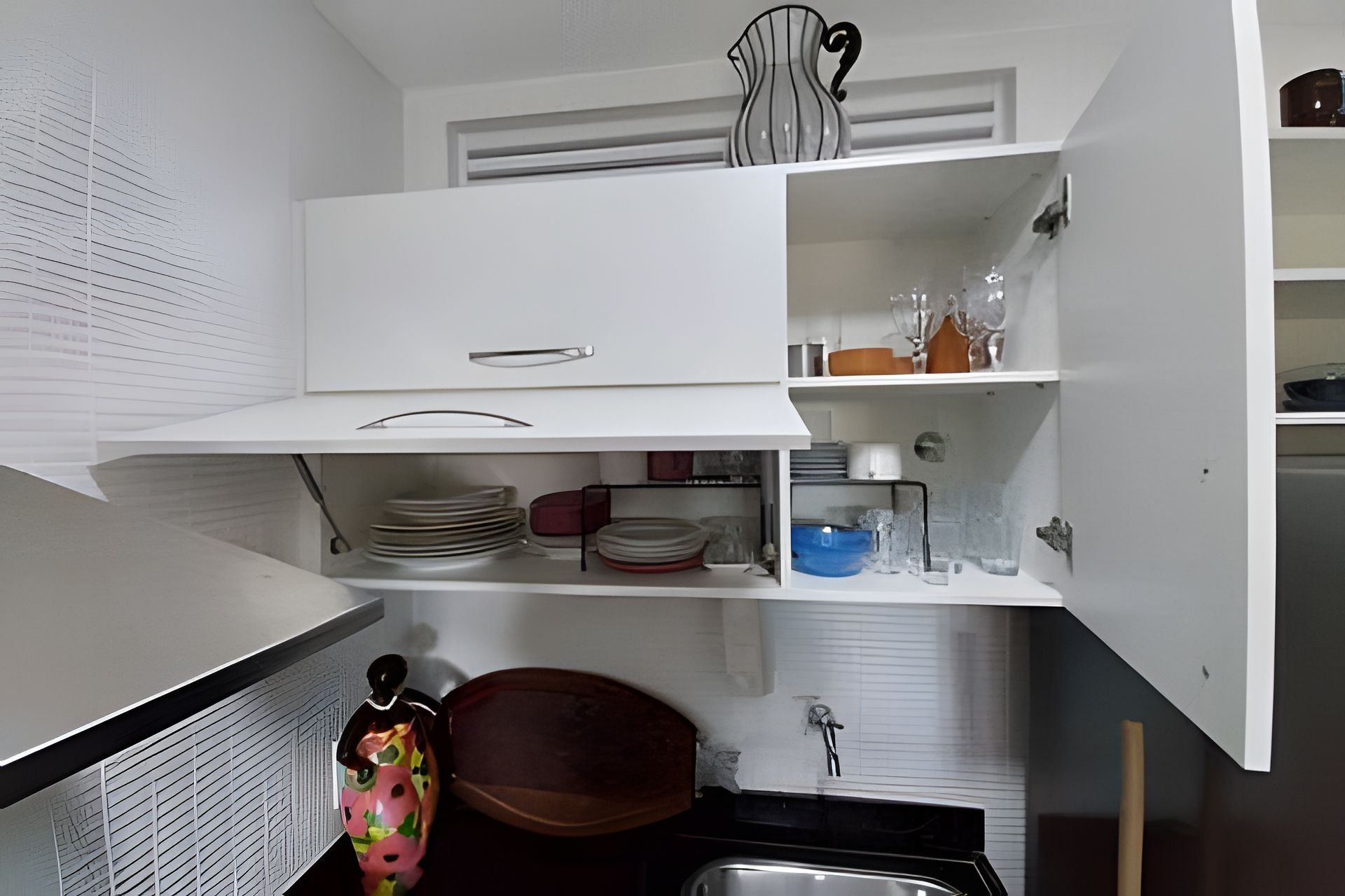 A kitchen with white cabinets, a sink, and a decorative vase.