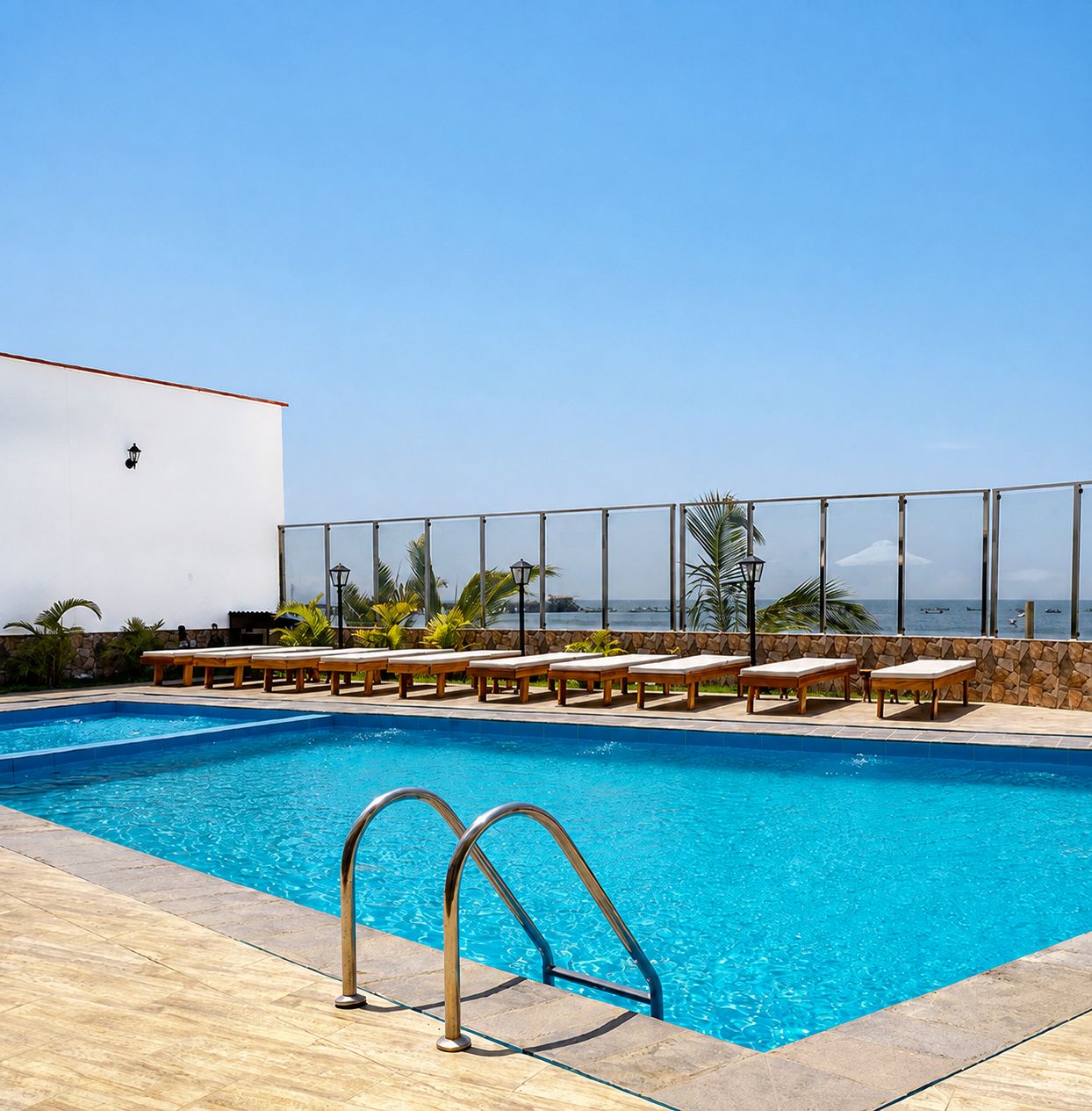 Piscina com espreguiçadeiras e vista para o oceano.
