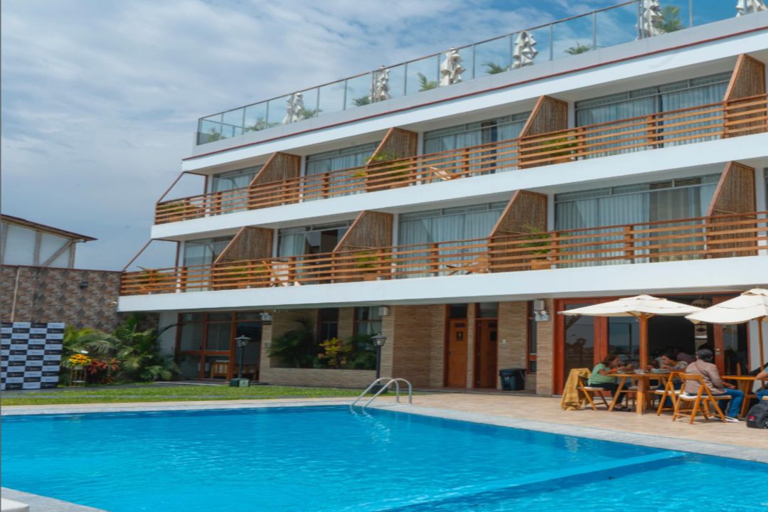 A hotel with a swimming pool, outdoor seating, and a multi-story structure with balconies.