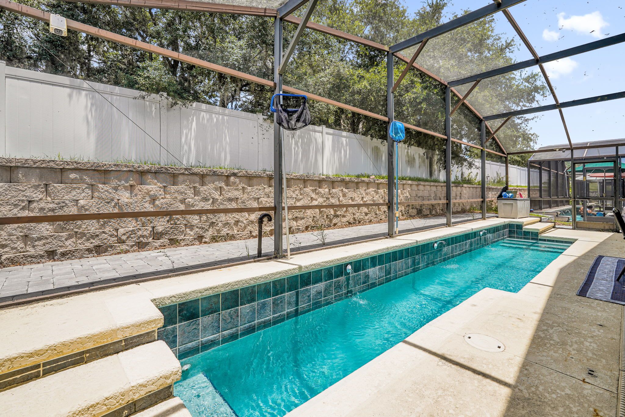 A swimming pool with a covered area, stone walls, and a metal structure.