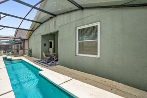 Una piscina con un porche cubierto, una puerta y una ventana con persianas.