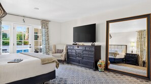 A hotel room with a bed, a dresser, a television, a large mirror, and a view of the outdoors through a glass door. - Casa Talavera by Avantstay Pool + Hot Tub + Fire Pit + BBQ Mins to Golf (Scottsdale)