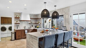 Una cocina moderna con una isla de mármol, armarios de madera y lavadora integrada.