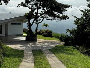 A modern building with a paved driveway leading to a covered patio area. - Villa Aleva: Private Pool, Panoramic Views & 30+ Night Stays (Atenas)