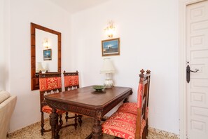 A dining area with a wooden table, chairs, a mirror, a wall-mounted picture, and a lamp. - Studio in Nerja Near Carabeillo Beach (Nerja)
