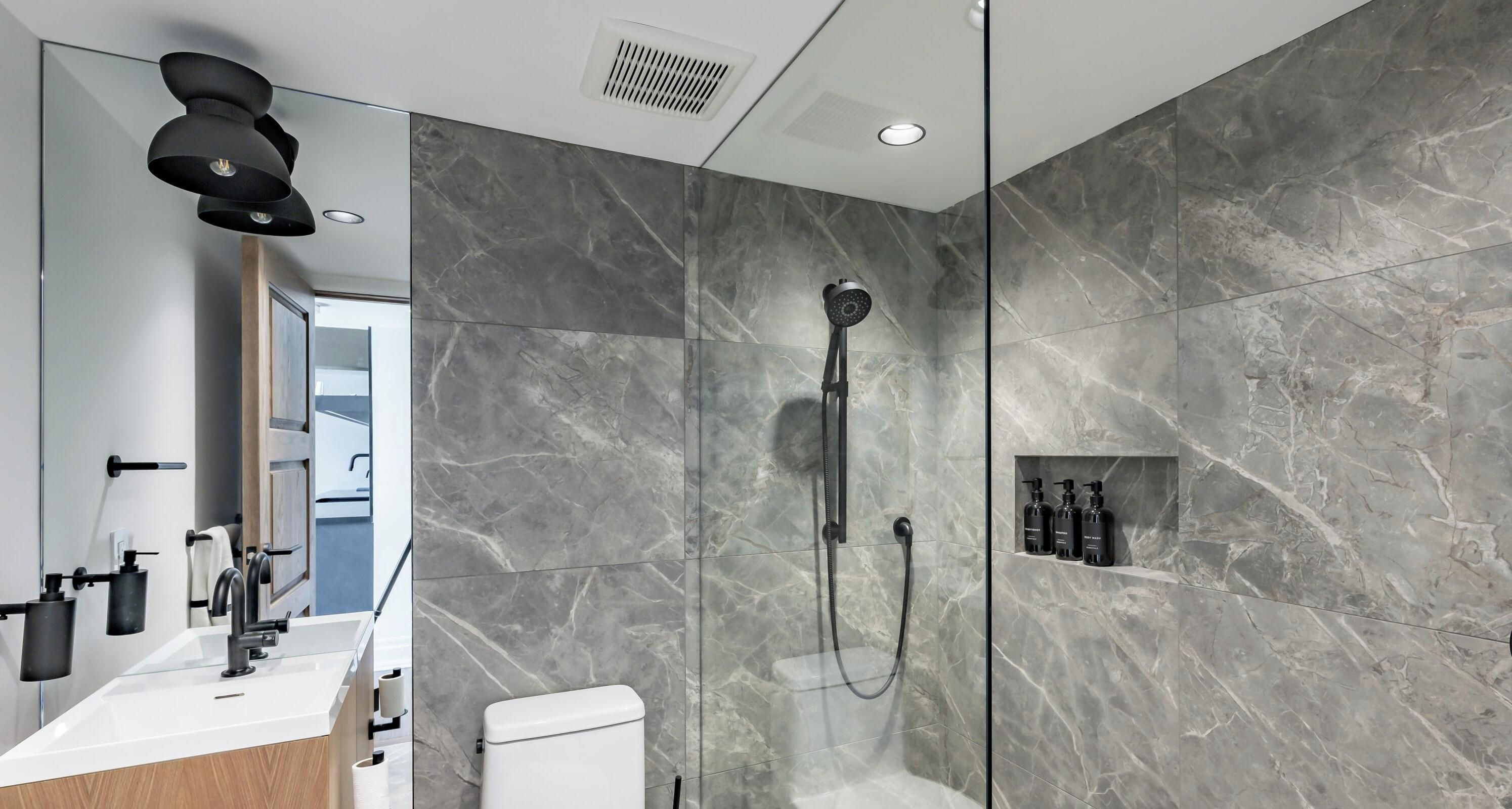 Een moderne badkamer met douche, toilet en wastafel.