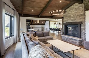Un salón amplio con un sofá modular grande, una chimenea y un comedor al fondo.