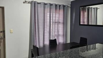 Una cocina moderna con encimera de granito, un comedor con sillas y un espejo grande en la pared.