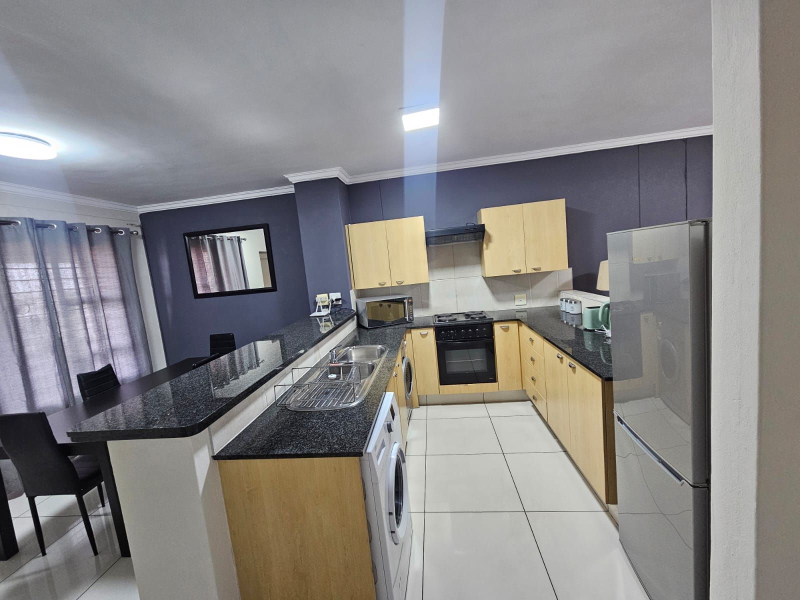 Una cocina compacta con horno integrado, lavadora y refrigerador.