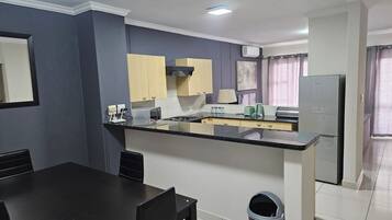 Una cocina moderna con una isla central, una mesa de comedor con sillas y un cubo de basura.