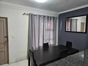 Quarto com uma mesa de jantar, cadeiras, uma porta e um espelho na parede.
