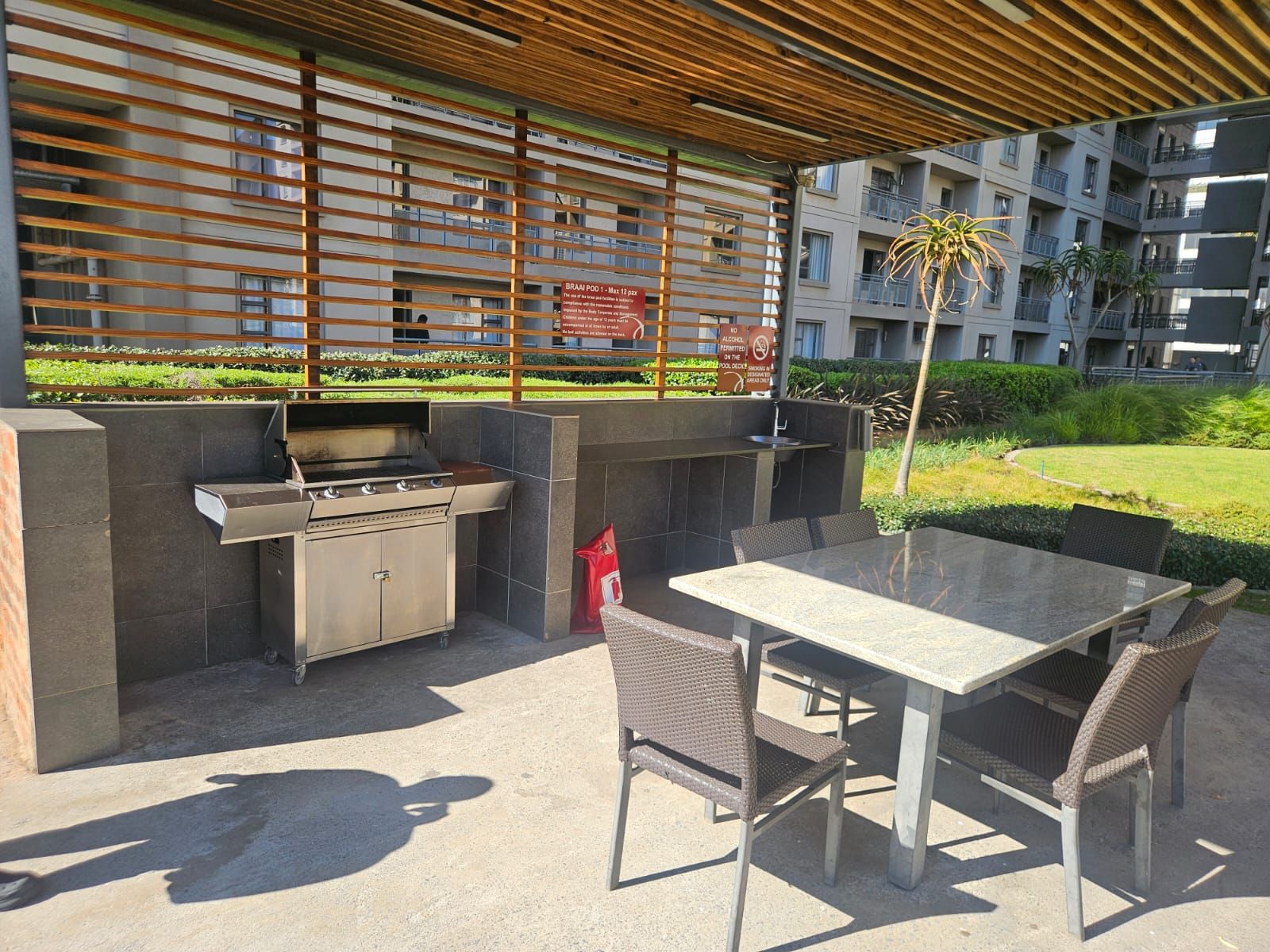 Un patio al aire libre con una parrilla, asientos y vistas a un edificio residencial.