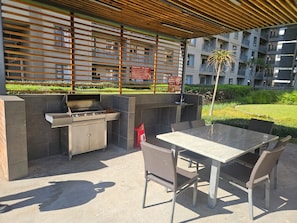 An outdoor patio with a grill, seating, and a view of a residential building. - Sandton Westpoint Luxury Apartments 176 (Sandton)