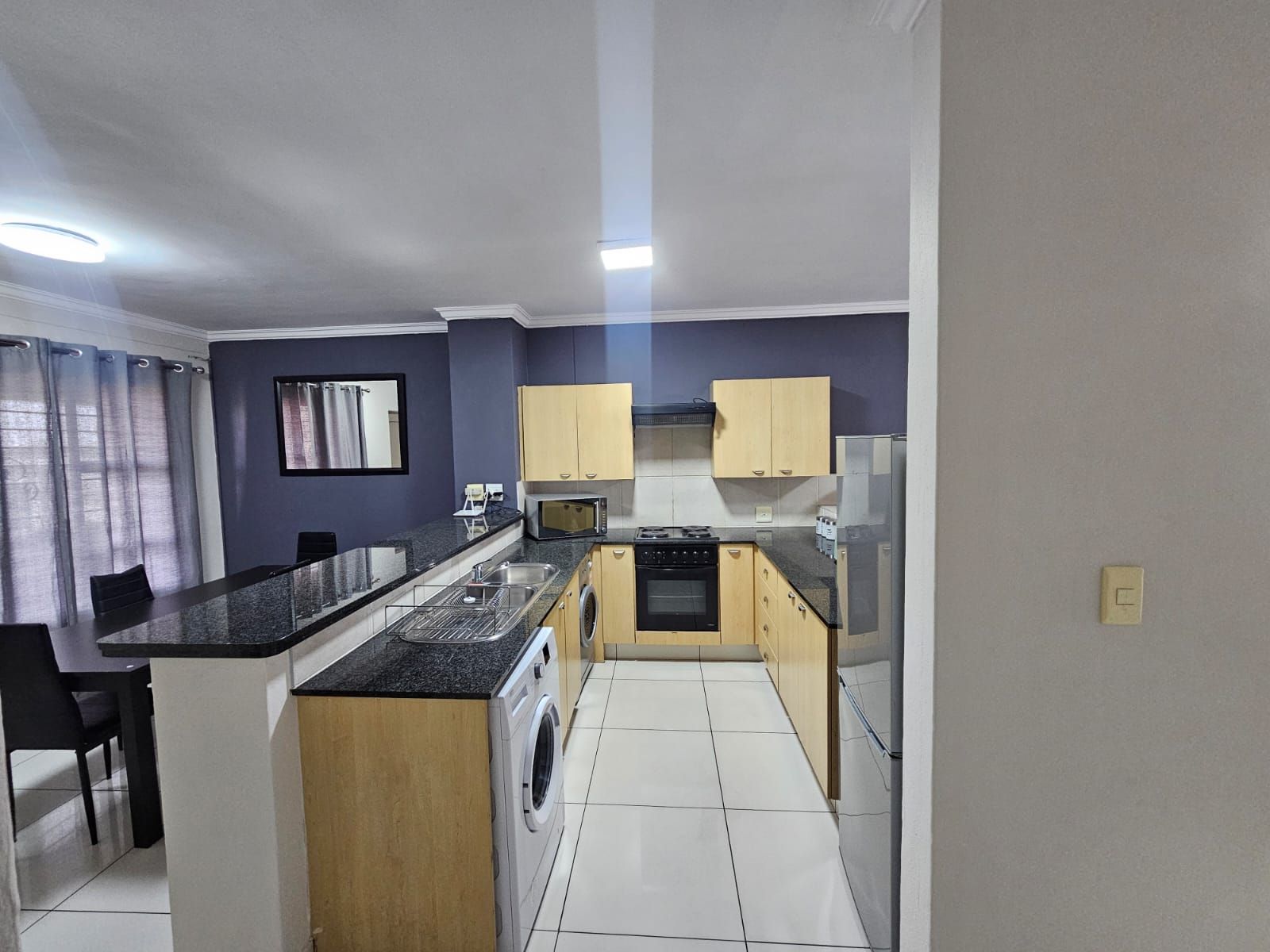 Una cocina compacta con una isla central, lavadora y microondas.
