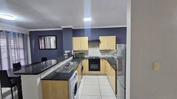 Una cocina compacta con una isla central, lavadora y microondas.