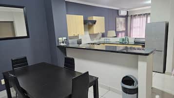 Una cocina compacta con comedor, un cubo de basura y un refrigerador.