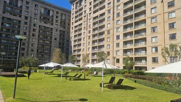 Un patio con mesas y sillas al aire libre, rodeado de edificios residenciales altos.