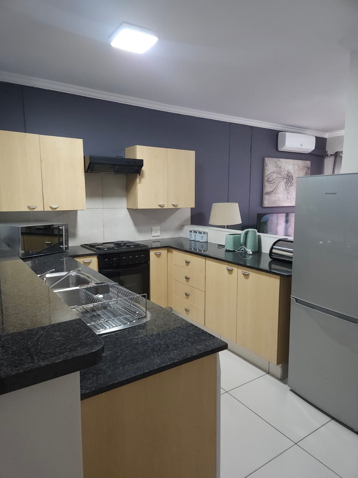 Una cocina equipada con estufa, microondas, pileta y alacenas.