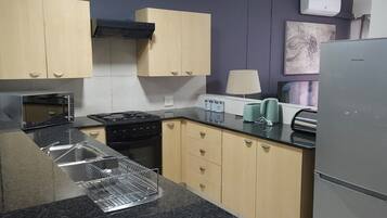 Una cocina equipada con estufa, microondas, pileta y alacenas.