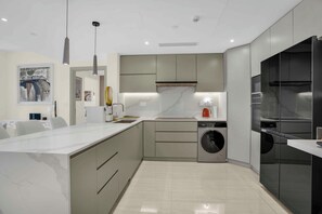 A modern kitchen with a marble countertop, built-in appliances, and a central island. - 2 Bed Apt Palm Views, Marina & Atlantis Panorama (Dubai)