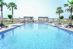 A swimming pool with lounge chairs and palm trees. - 2 Bed Apt Palm Views, Marina & Atlantis Panorama (Dubai)