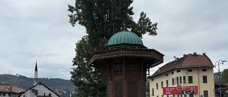 A public square with a central gazebo, surrounding buildings, and people walking.